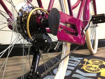 A close up of the gears on a purple city bike